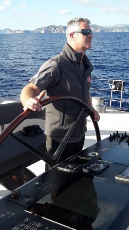 Sacha de Rechter aan het roer van een zeiljacht op open water